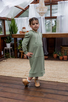 Young girl wearing Nuggles® Zoelle Dress in solid color, modest hoodie dress with puff sleeves.