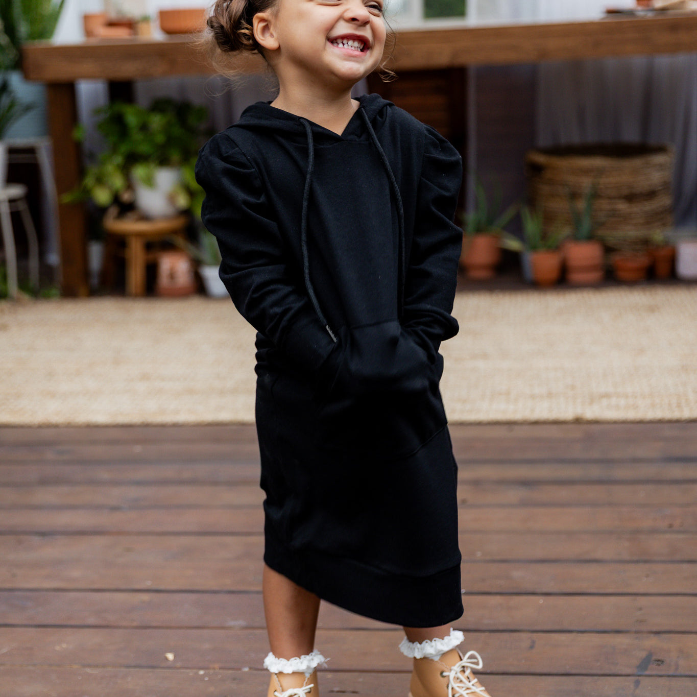 Young girl wearing Nuggles® Zoelle Dress in solid color, modest hoodie dress with puff sleeves.