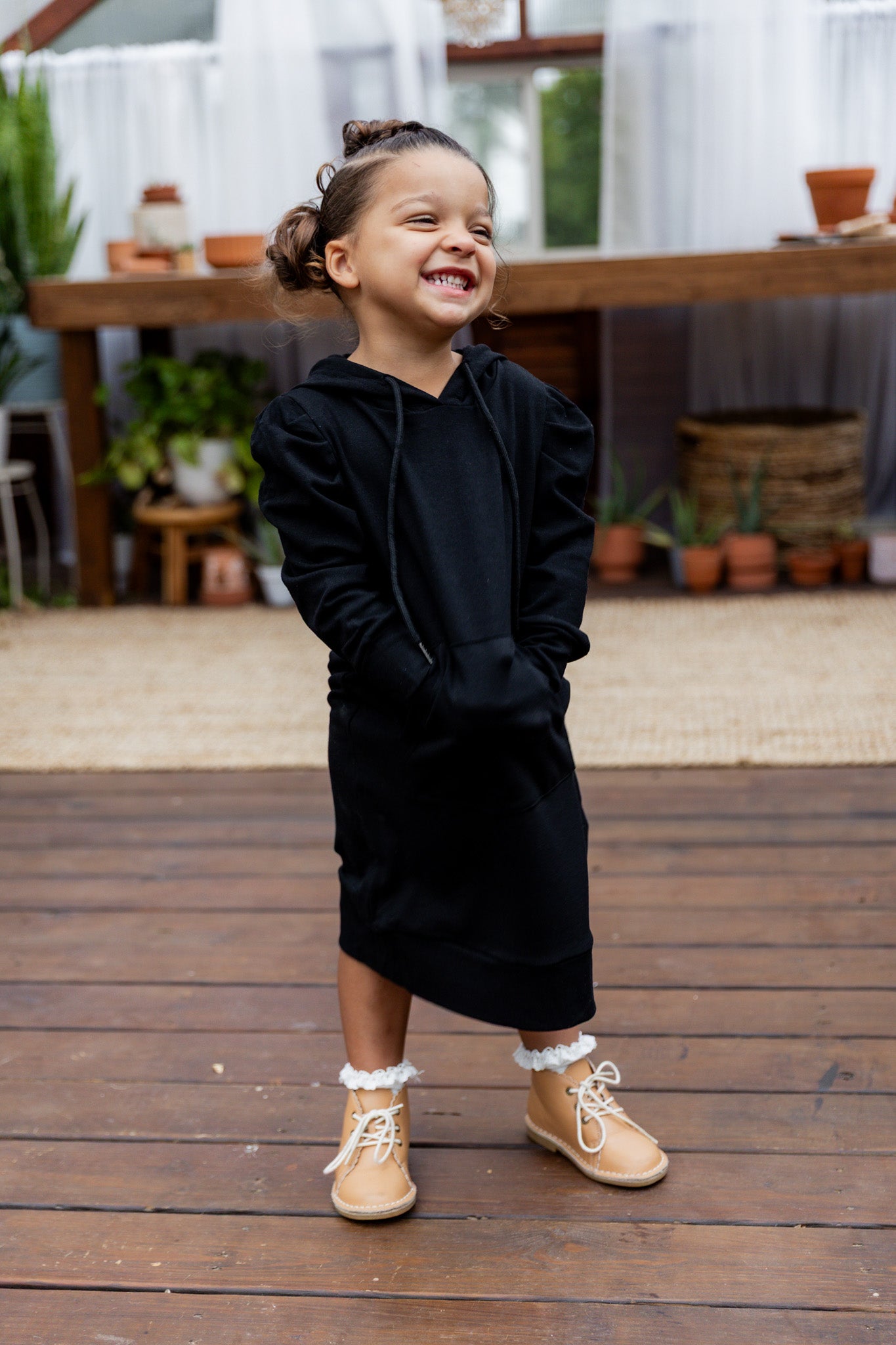 Young girl wearing Nuggles® Zoelle Dress in solid color, modest hoodie dress with puff sleeves.