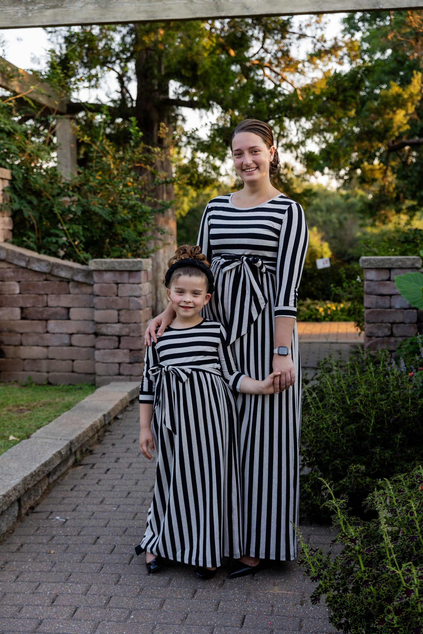 Model wearing the Nuggles® Adelia Dress, a modest striped maxi dress with waist tie and ¾ sleeves.