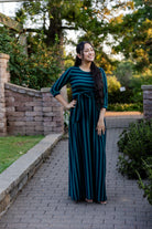 Model wearing the Nuggles® Adelia Dress, a modest striped maxi dress with waist tie and ¾ sleeves.