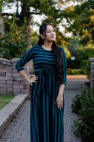 Model wearing the Nuggles® Adelia Dress, a modest striped maxi dress with waist tie and ¾ sleeves.