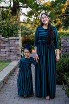 Model wearing the Nuggles® Adelia Dress, a modest striped maxi dress with waist tie and ¾ sleeves.