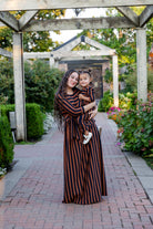 Model wearing the Nuggles® Adelia Dress, a modest striped maxi dress with waist tie and ¾ sleeves.