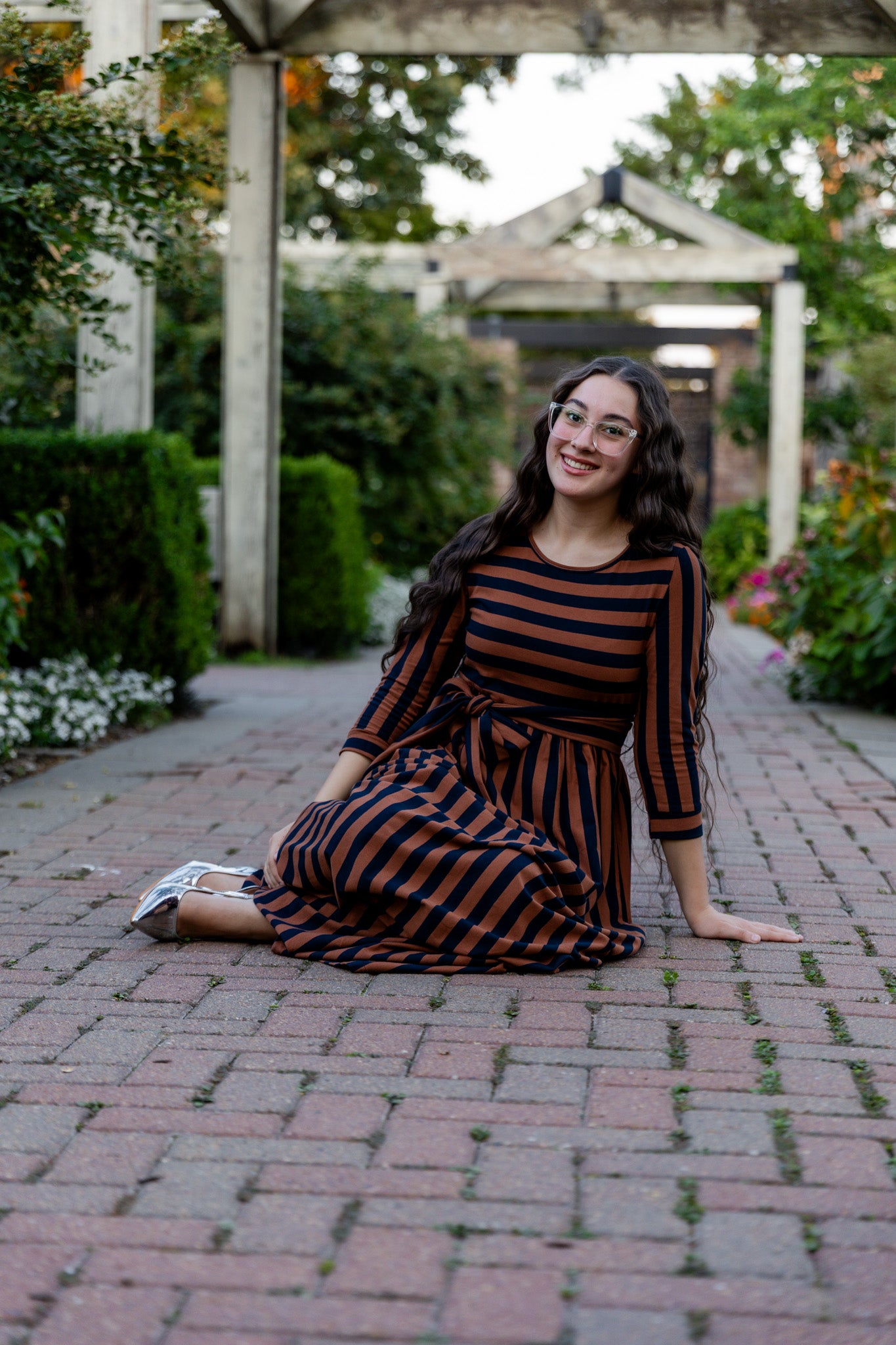 Model wearing the Nuggles® Adelia Dress, a modest striped maxi dress with waist tie and ¾ sleeves.