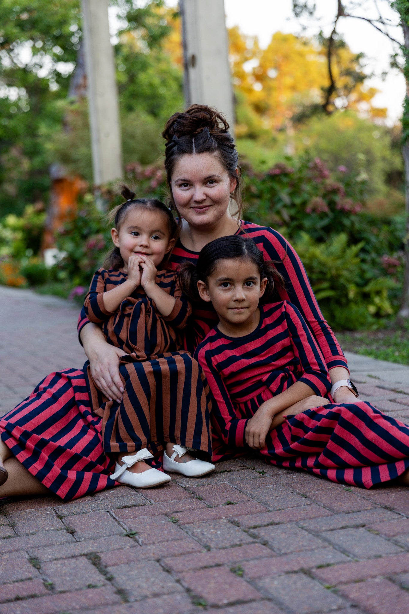Young girl wearing the Nuggles® Girls Adelia Dress — a modest striped maxi dress with bow tie waist.
