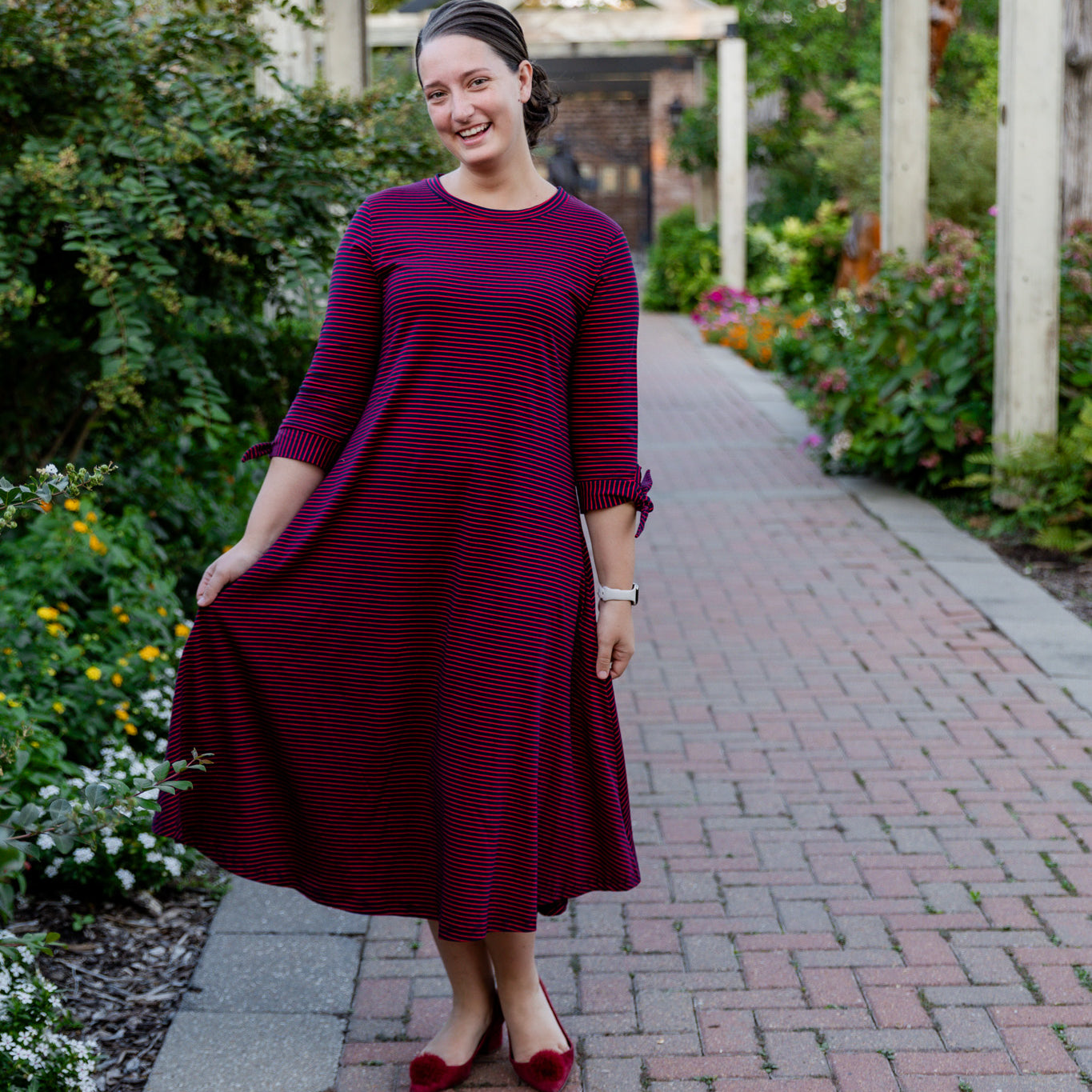 Model wearing the Nuggles® Gracie Dress, a modest A-line midi dress with ¾ sleeves and tie accents, made from soft knit fabric.