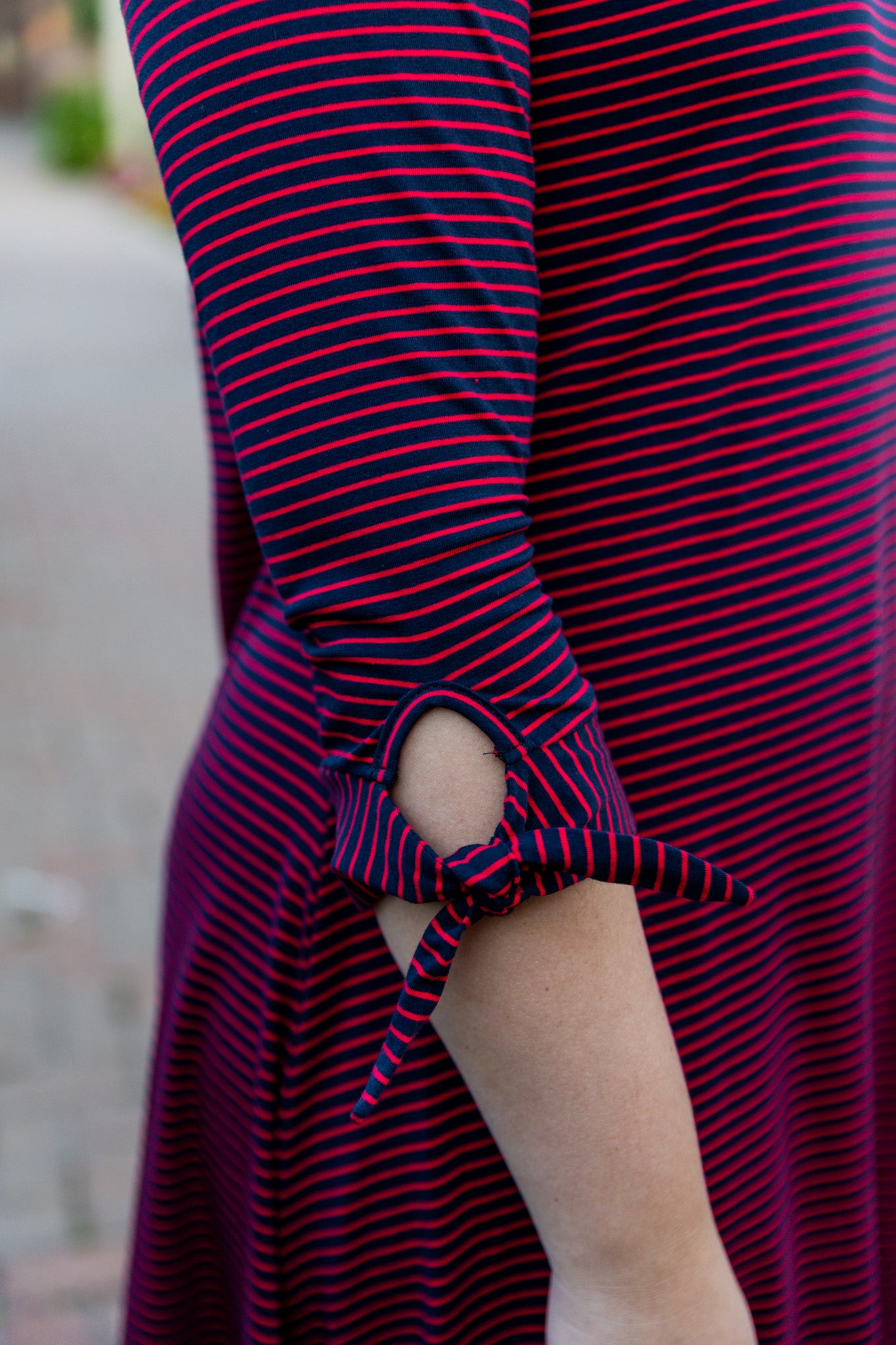 Model wearing the Nuggles® Gracie Dress, a modest A-line midi dress with ¾ sleeves and tie accents, made from soft knit fabric.