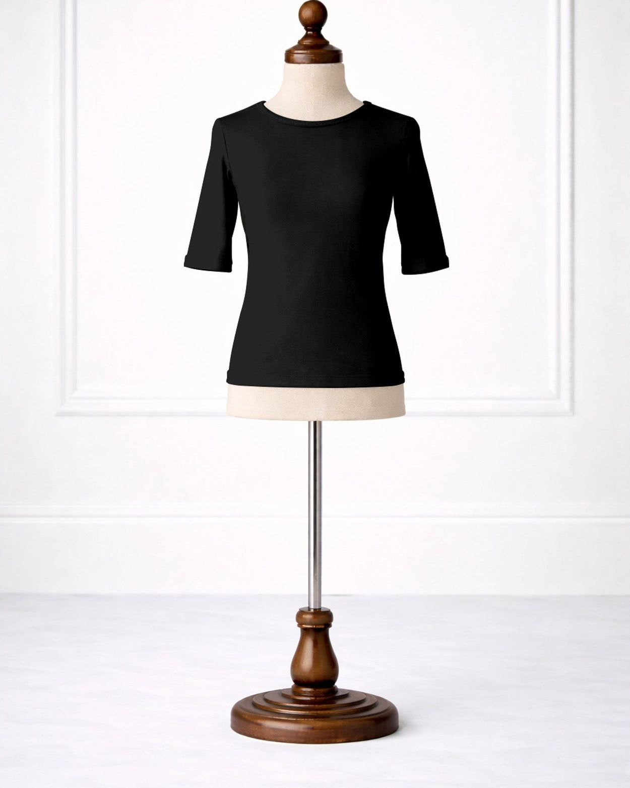 Black top on a mannequin with a wooden base against a white background