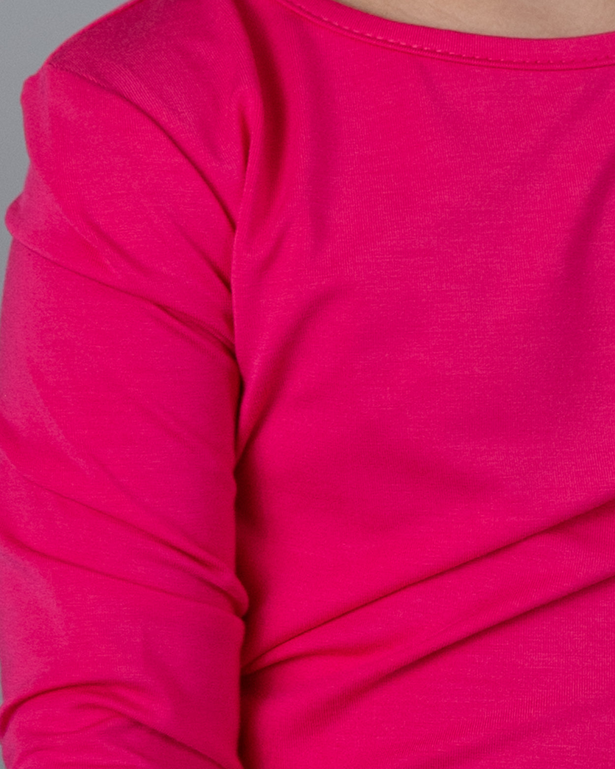 Close-up of a bright pink long-sleeve shirt on a neutral background