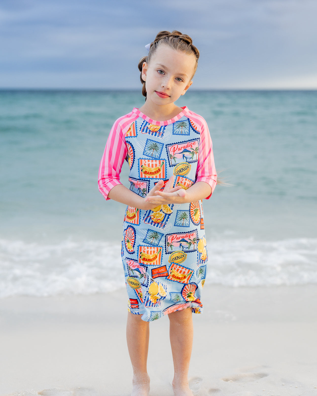 Model wearing Nuggles® Girls' Sport Swim Dress in Vacation Postcards