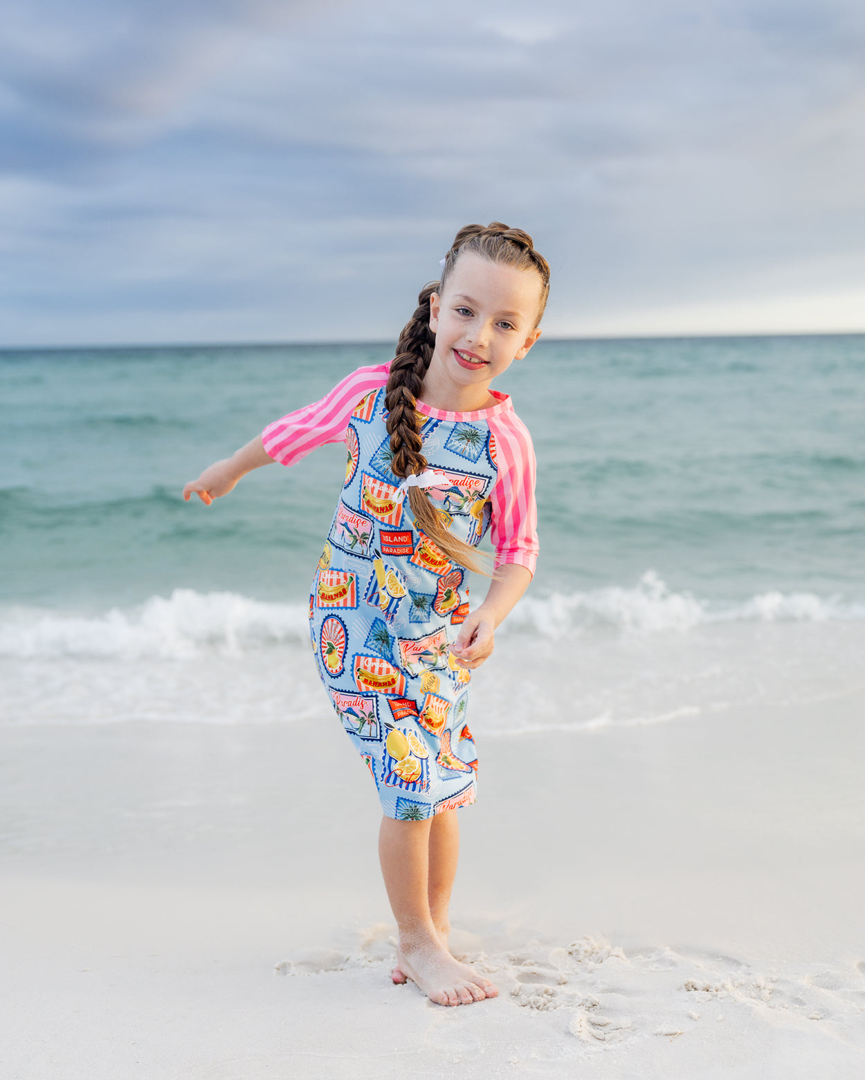 Model wearing Nuggles® Girls' Sport Swim Dress in Vacation Postcards