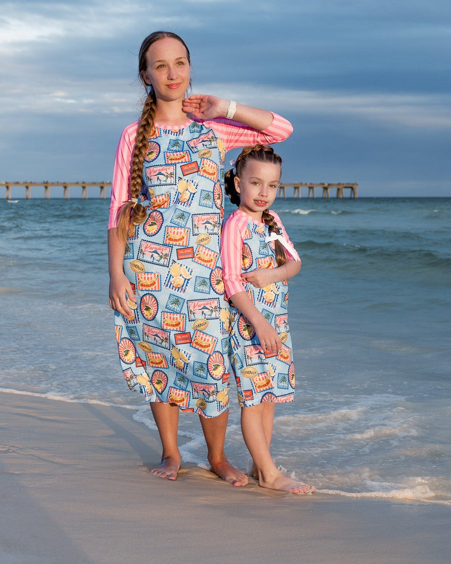 Model wearing Nuggles® Sport Swim Dress in Vacation Postcards