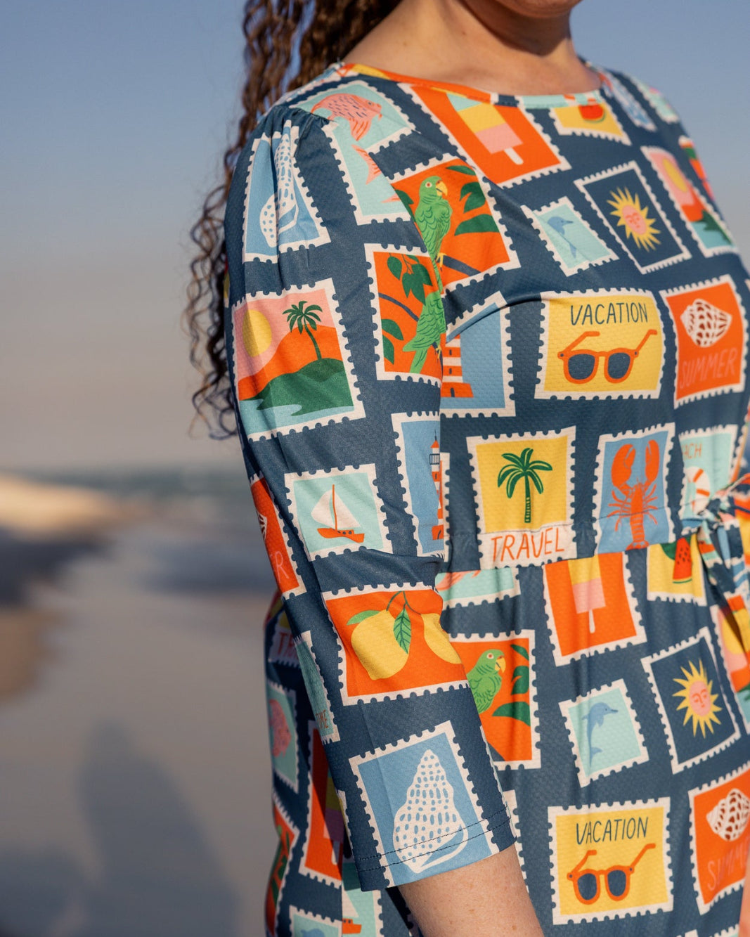 Model wearing Nuggles® Nola Sport Swim Dress in Retro Postcards