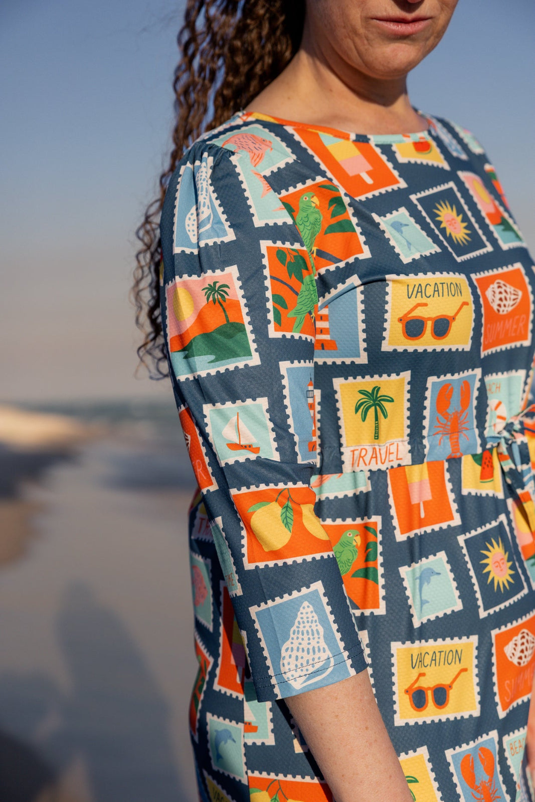 Model wearing Nuggles® Nola Sport Swim Dress in Retro Postcards