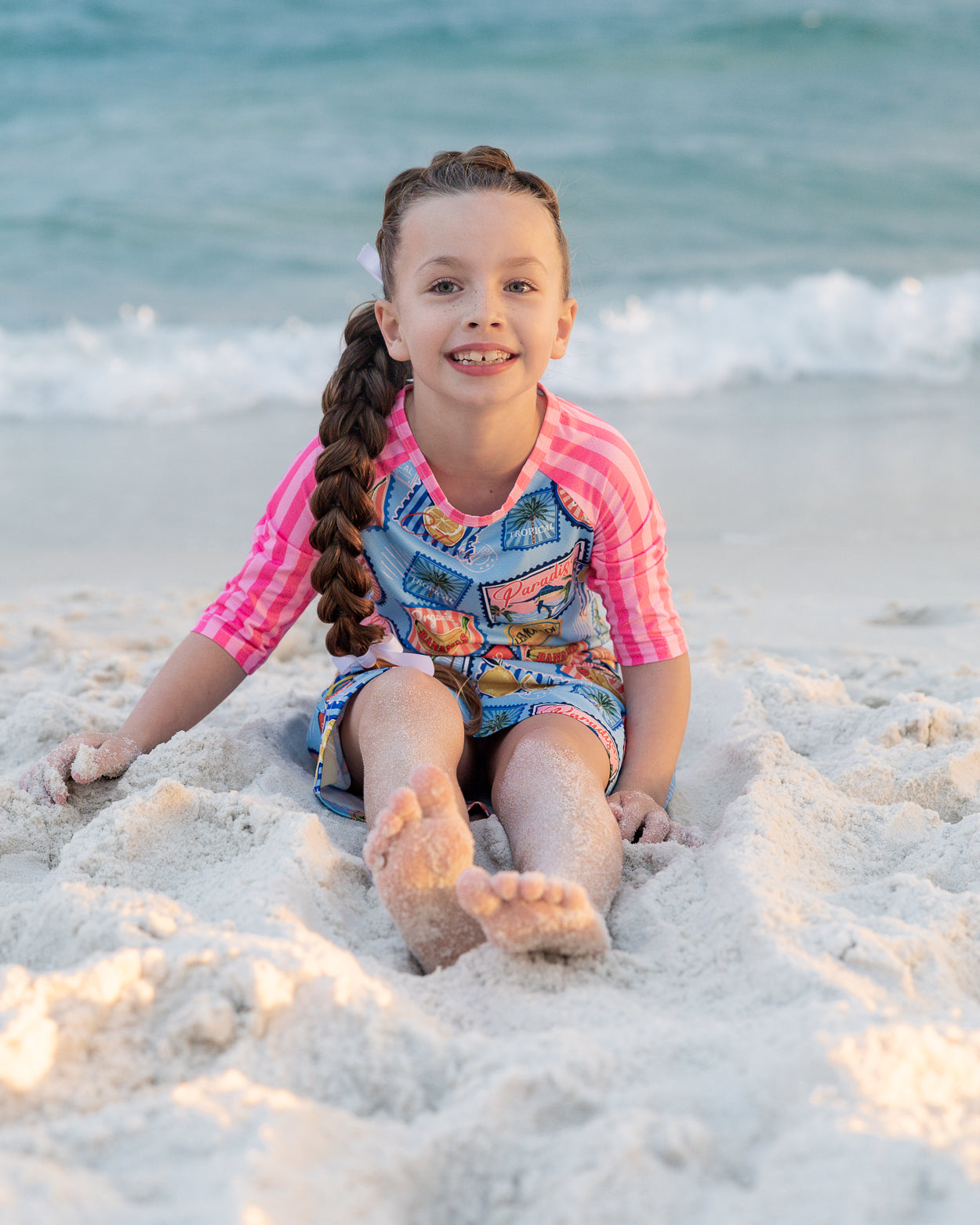 Model wearing Nuggles® Girls' Sport Swim Dress in Vacation Postcards