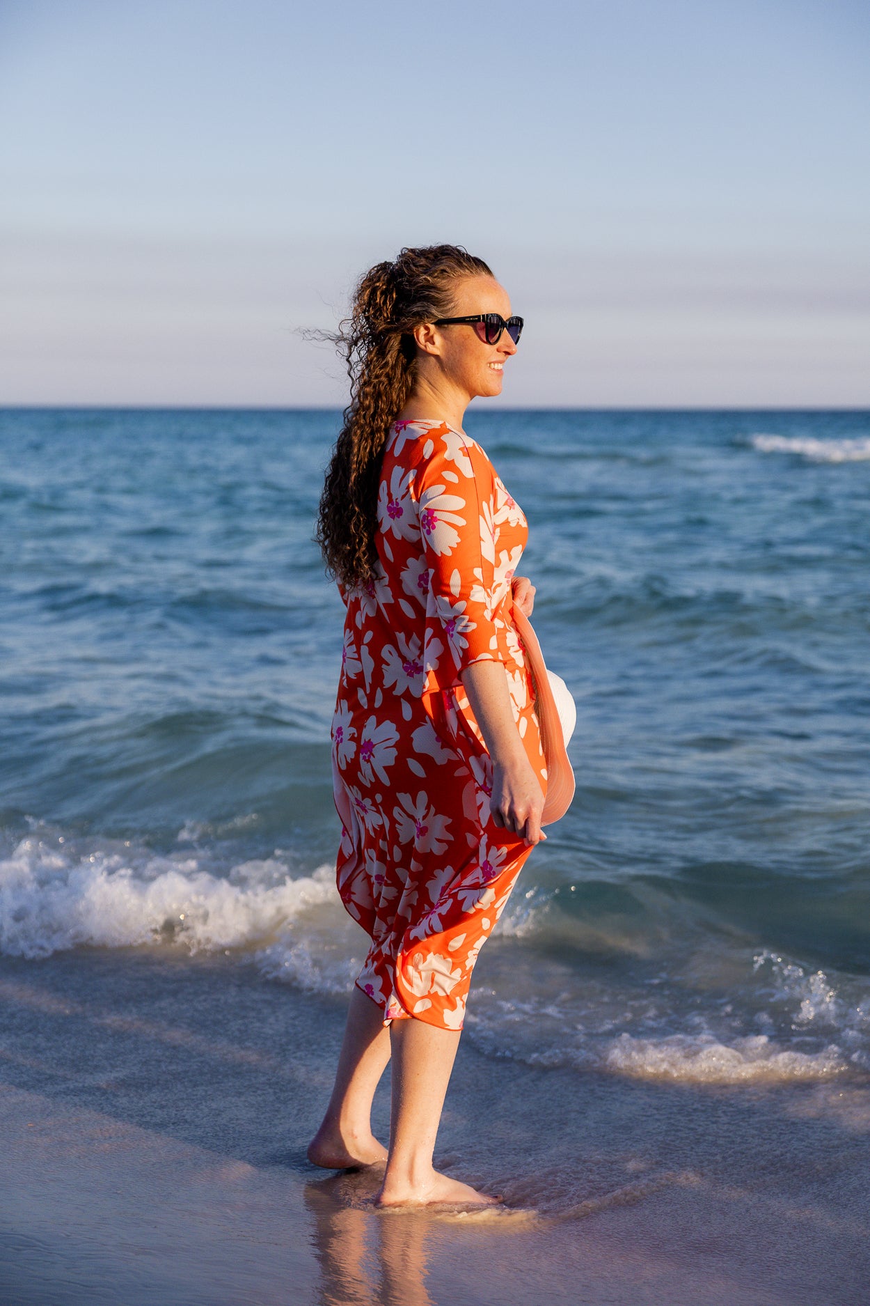 Model wearing Nuggles® Carlie Swim Dress in Sunset Hibiscus