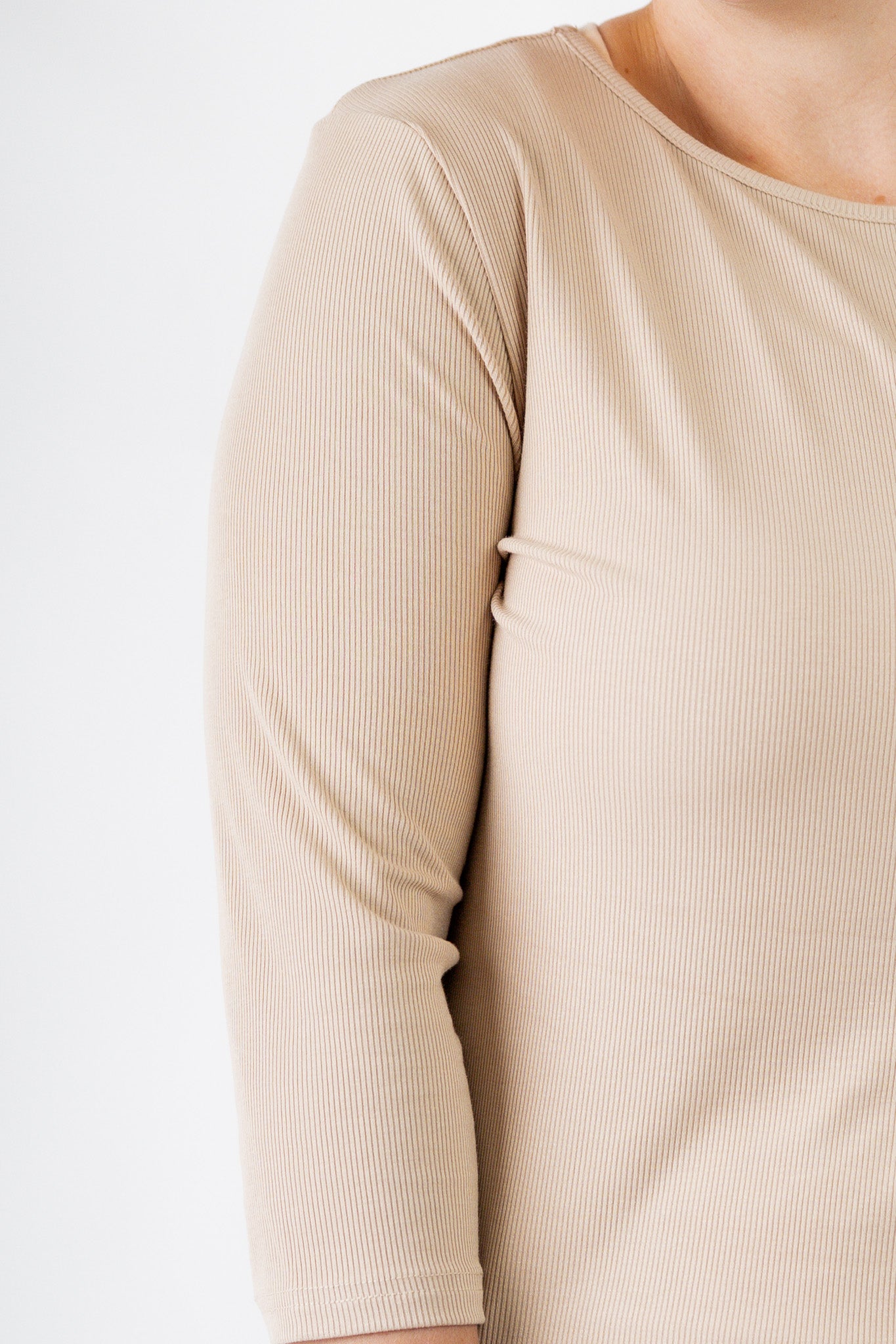 Model wearing the  Nuggles®  Essential 3/4 Tee in ribbed fabric, a modest, fitted top with 3/4 sleeves and a rounded neckline. Shown in a neutral tone, ideal for layering.