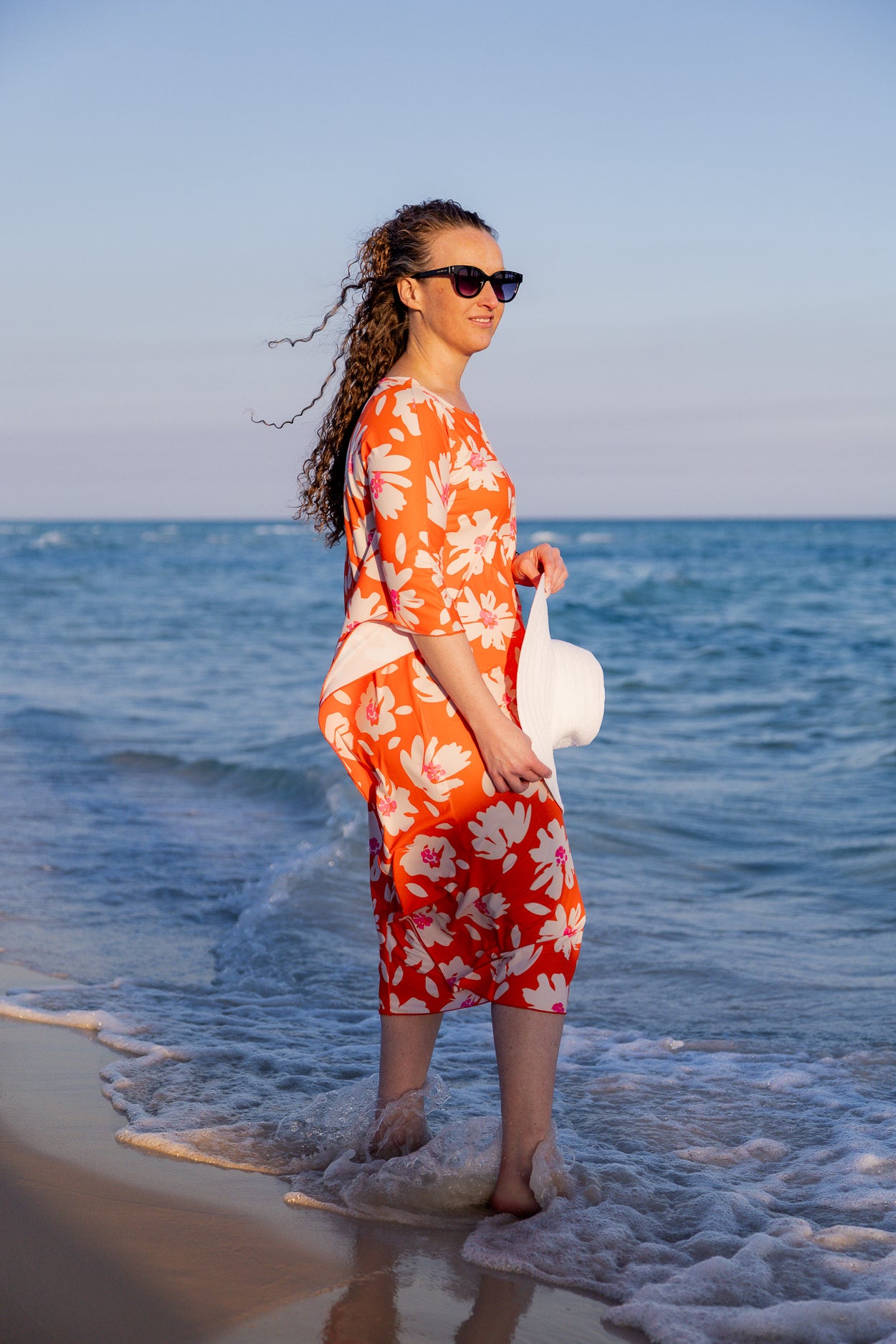 Model wearing Nuggles® Carlie Swim Dress in Sunset Hibiscus