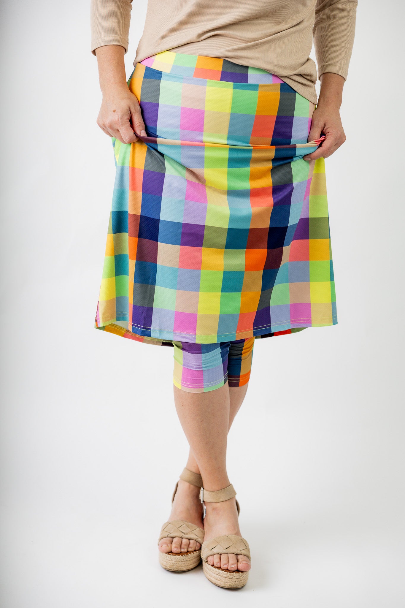 Model wearing Nuggles® Jaxon Plaid 27-inch All Sport Skirt with built-in leggings, featuring vibrant multicolor plaid pattern. Modest athletic skirt for women, designed for activewear and everyday comfort.