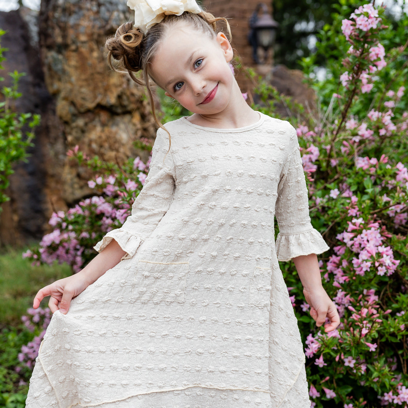 Girls Daphne Dress in textured fabric – front view.