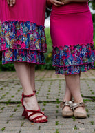 Model wearing a bright magenta 27" slip skirt with a colorful tropical floral ruffle design.