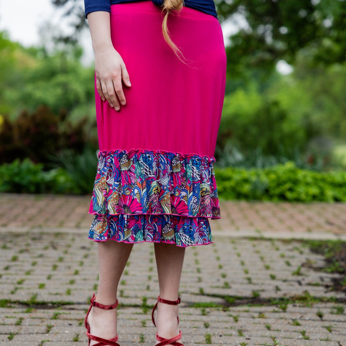 Model wearing a bright magenta 27" slip skirt with a colorful tropical floral ruffle design.