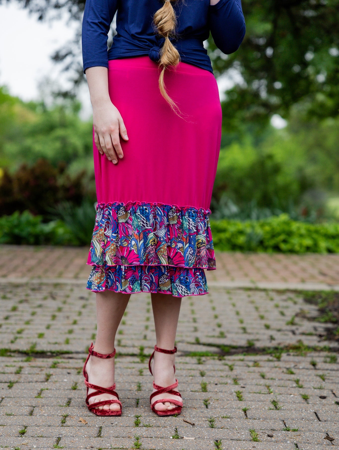 Model wearing a bright magenta 27" slip skirt with a colorful tropical floral ruffle design.