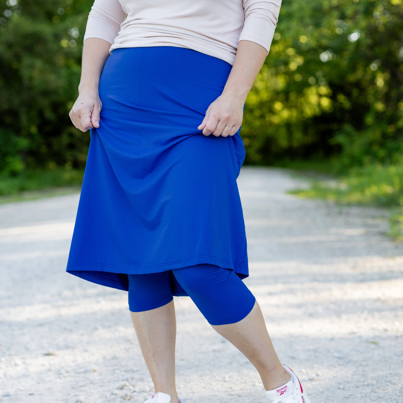 Woman wearing 27-inch blue modest sport skirt with built-in leggings—ideal for activewear, cycling, running, swimming, and workouts.