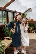 Young girl wearing Nuggles® Zoelle Dress in solid color, modest hoodie dress with puff sleeves.