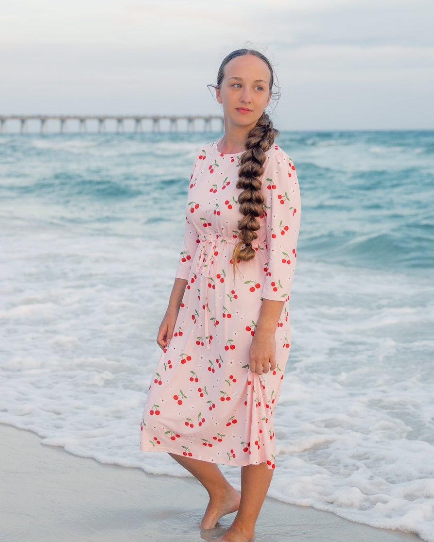 Model wearing Nuggles® Nola Sport Swim Dress in Cherry Soda Shop