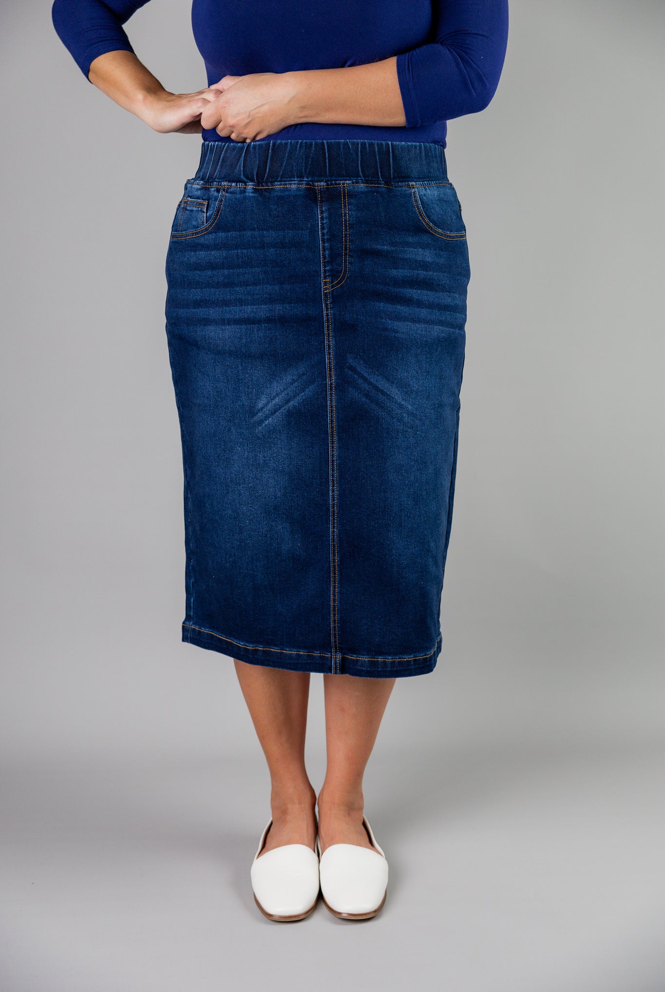 Nuggles® denim midi skirt with soft stretch fabric, wide elastic waistband, modest length, and functional pockets. Available in 27", 31", and 34" lengths.