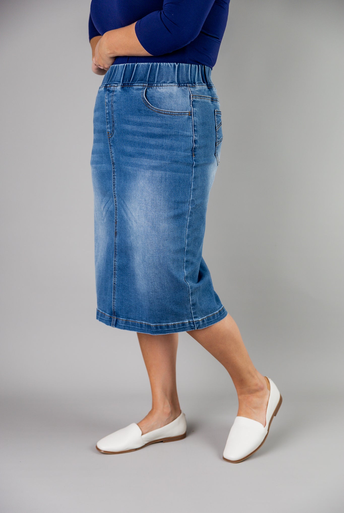 Nuggles® denim midi skirt with soft stretch fabric, wide elastic waistband, modest length, and functional pockets. Available in 27", 31", and 34" lengths.