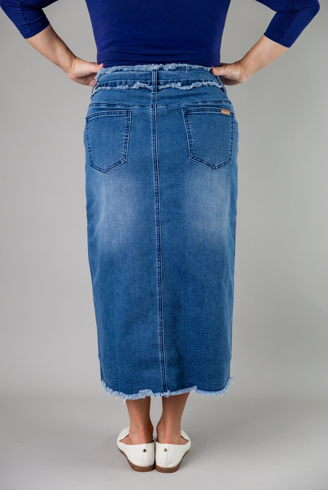 Nuggles® denim midi skirt with soft stretch fabric, wide elastic waistband, modest length, and functional pockets. Available in 27", 31", and 34" lengths.