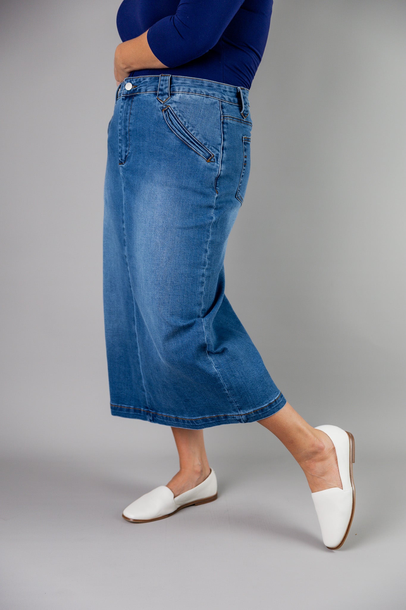 Nuggles® denim midi skirt with soft stretch fabric, wide elastic waistband, modest length, and functional pockets. Available in 27", 31", and 34" lengths.