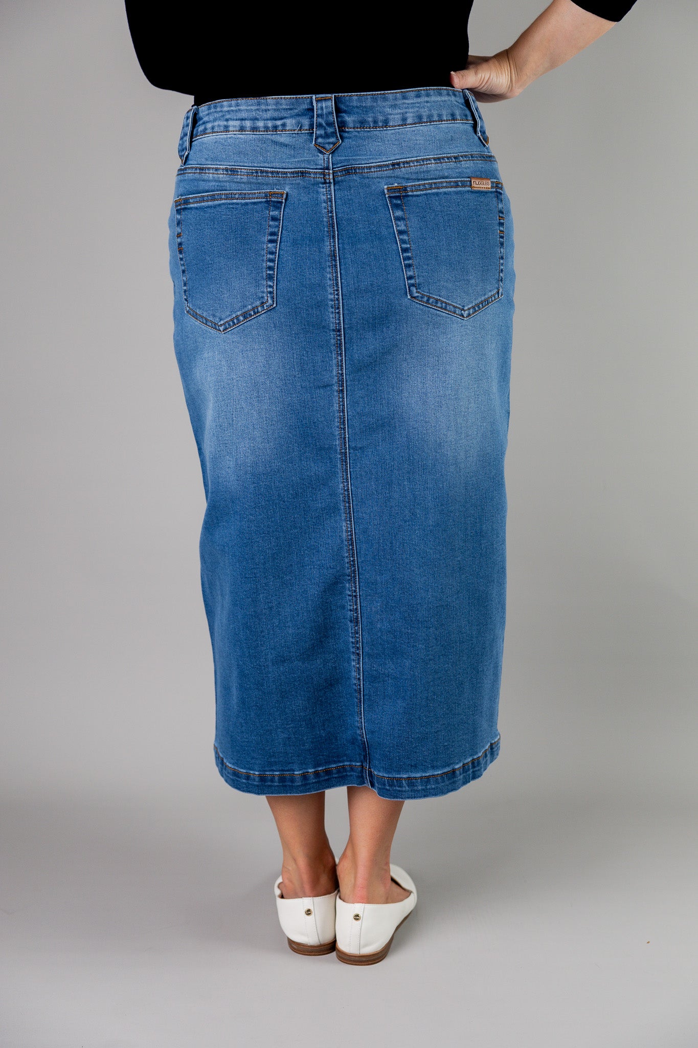 Nuggles® denim midi skirt with soft stretch fabric, wide elastic waistband, modest length, and functional pockets. Available in 27", 31", and 34" lengths.