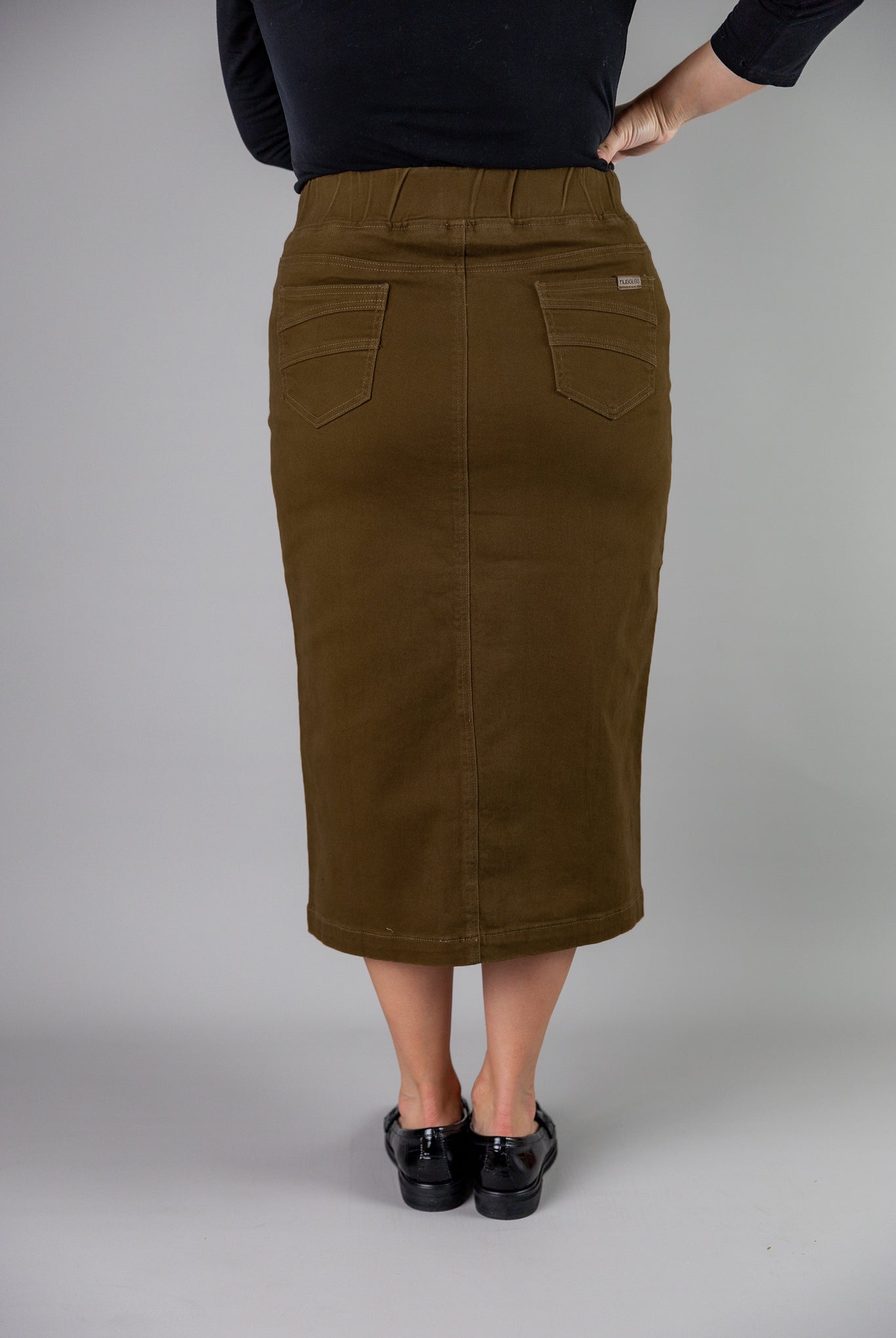 Nuggles® denim midi skirt with soft stretch fabric, wide elastic waistband, modest length, and functional pockets. Available in 27", 31", and 34" lengths.