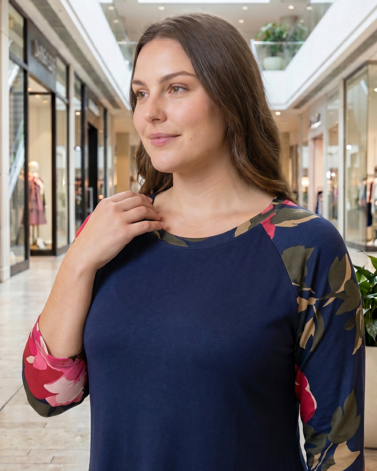 Woman modeling a navy floral-sleeve top in a mall.