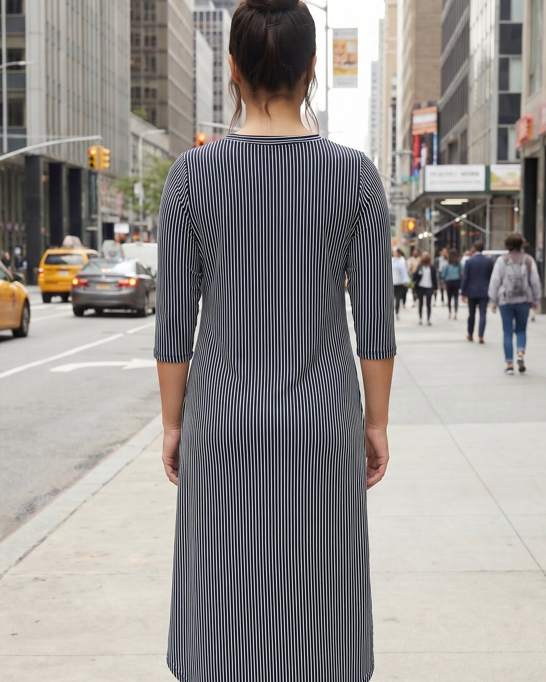 Woman in a striped dress standing on a city street