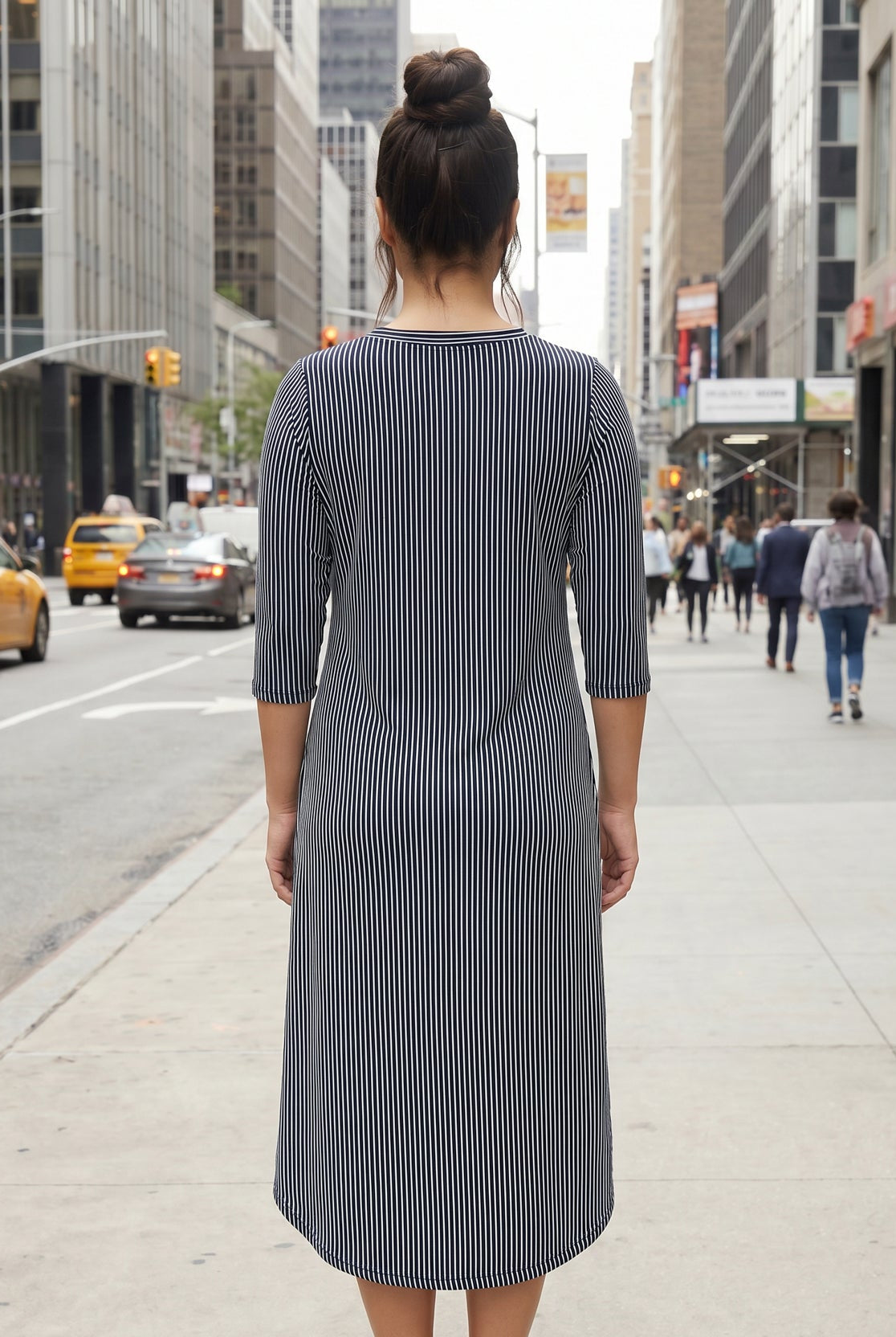 Woman in a striped dress standing on a city street