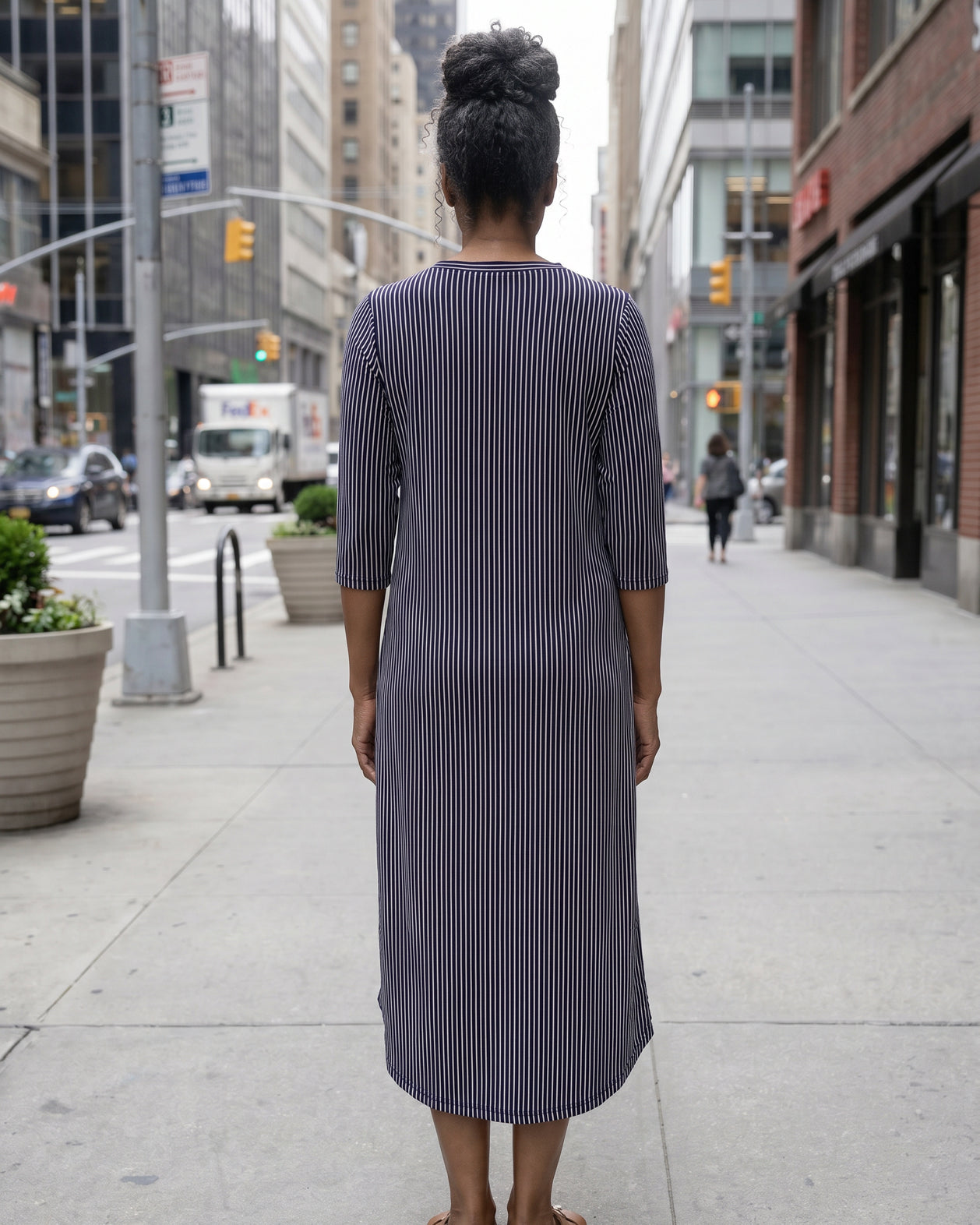 Women standing in a navy and pink stripe dress on a busy city street.