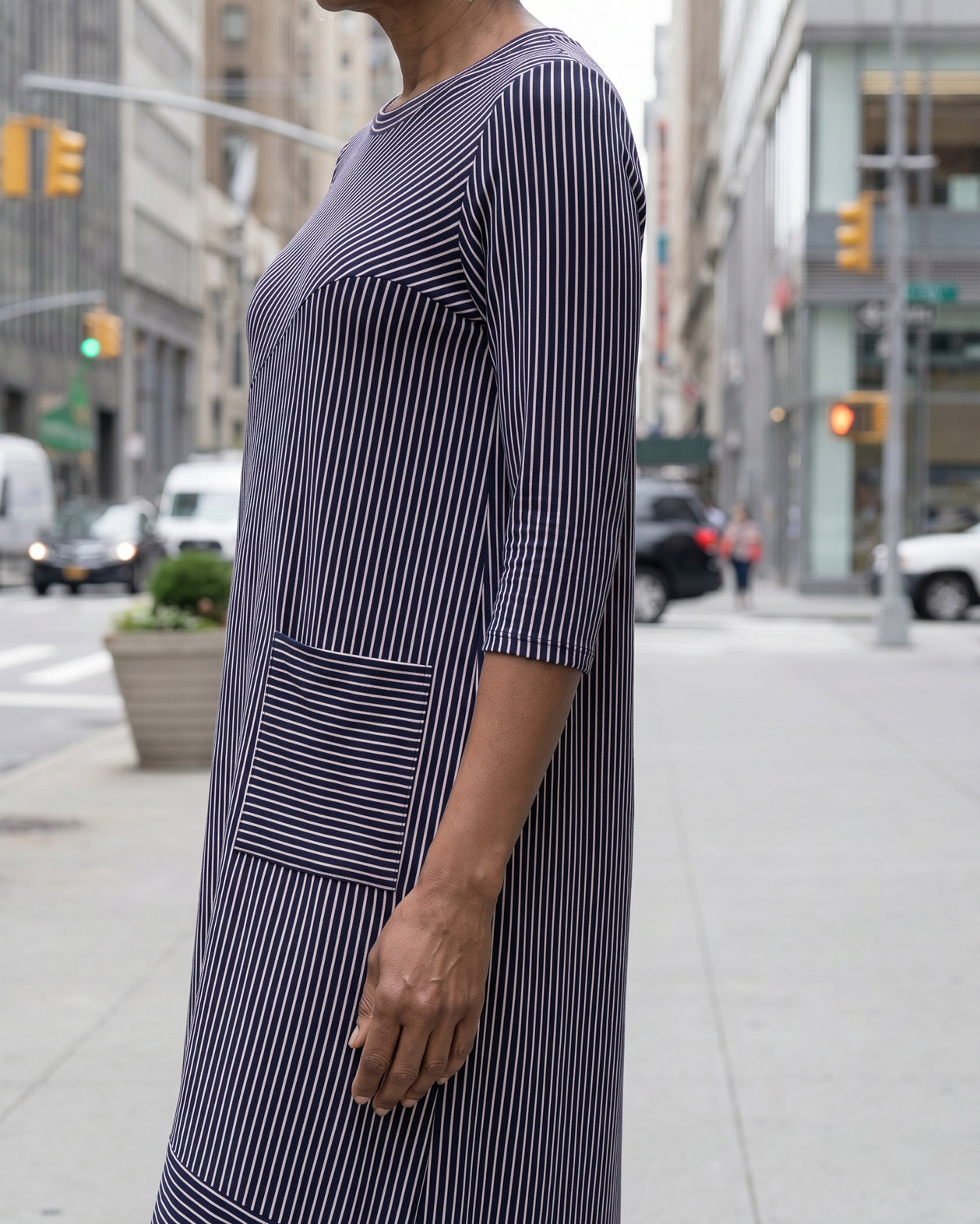 Women standing in a navy and pink stripe dress on a busy city street.