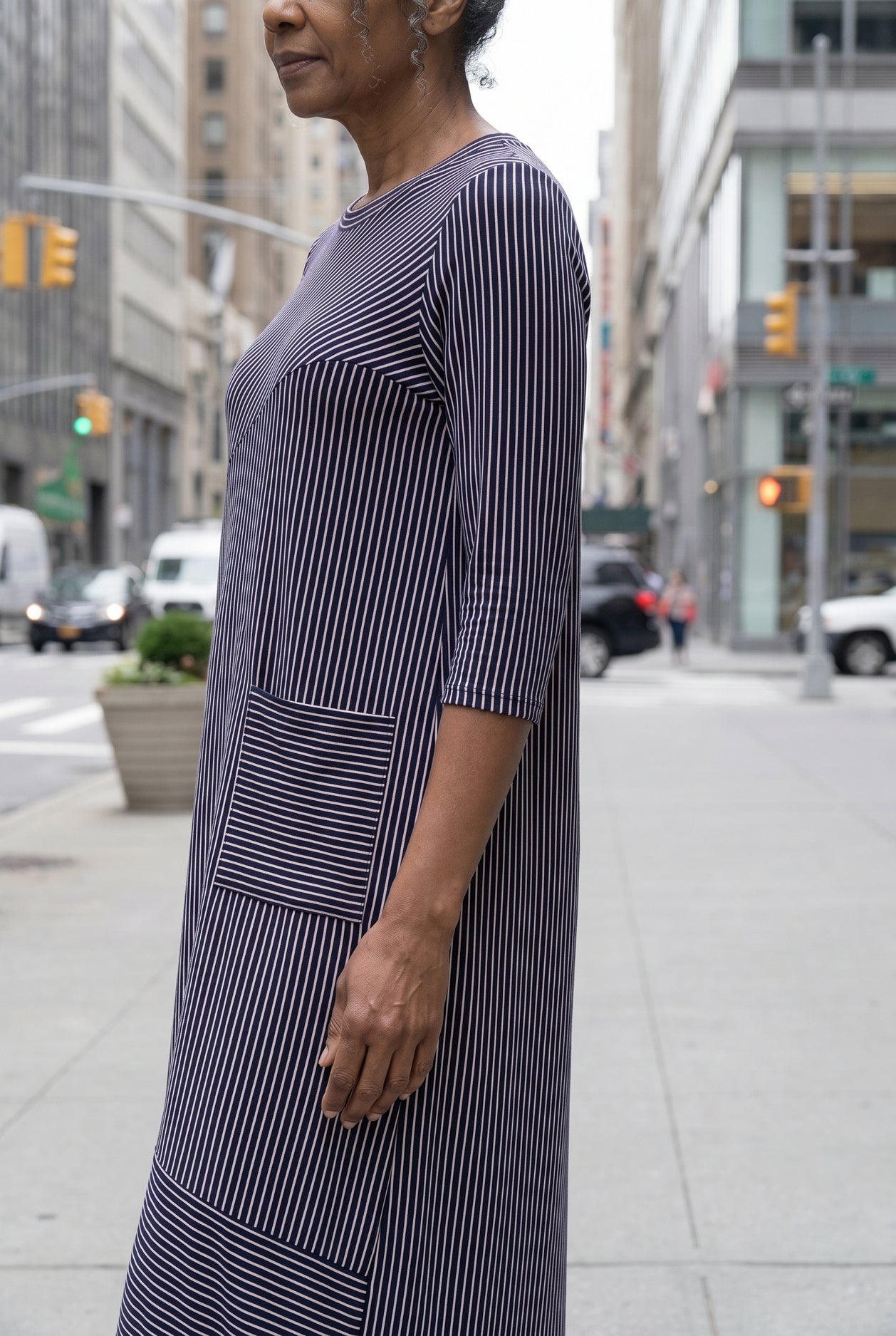 Women standing in a navy and pink stripe dress on a busy city street.