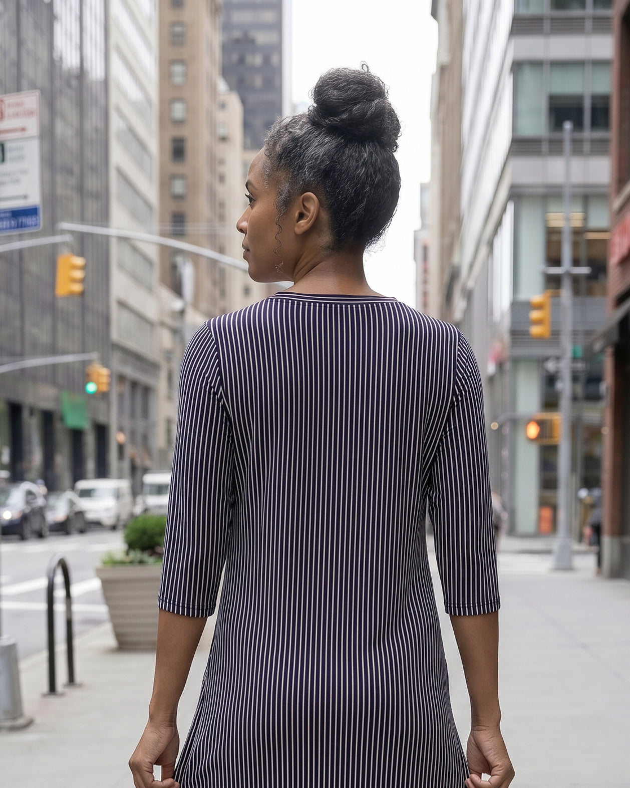Women standing in a navy and pink stripe dress on a busy city street.