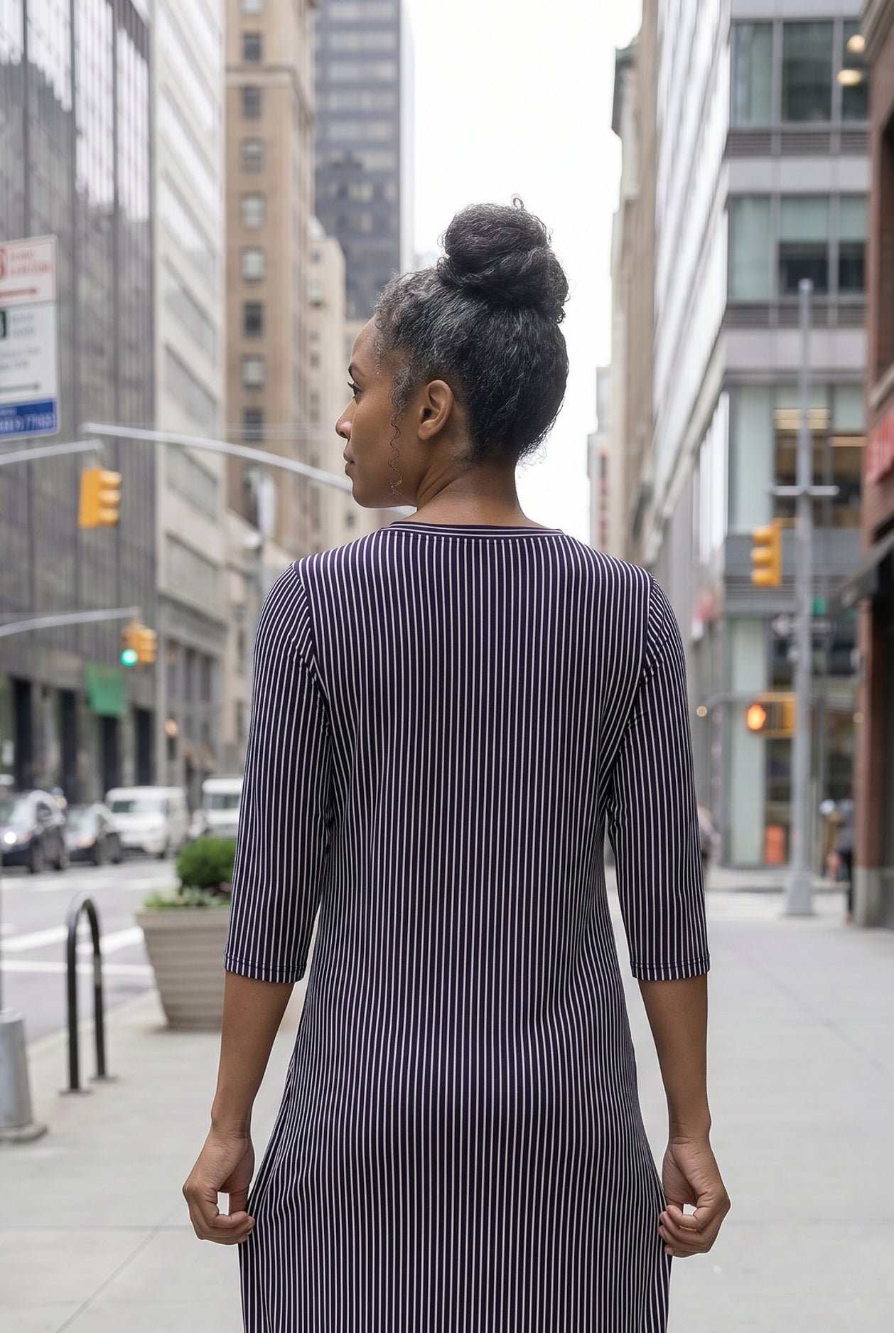 Women standing in a navy and pink stripe dress on a busy city street.