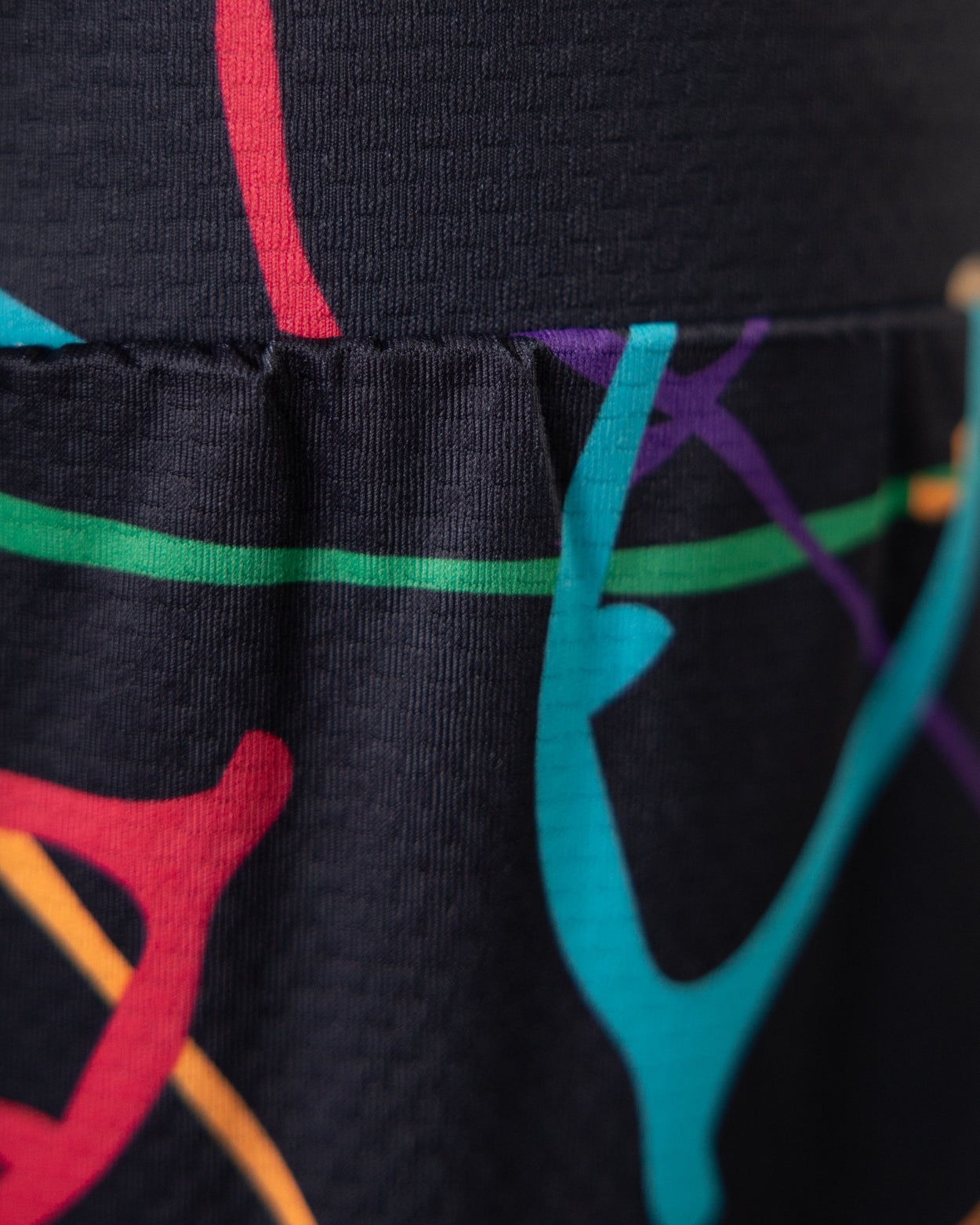 Close-up of black leggings with colorful abstract designs on a plain background