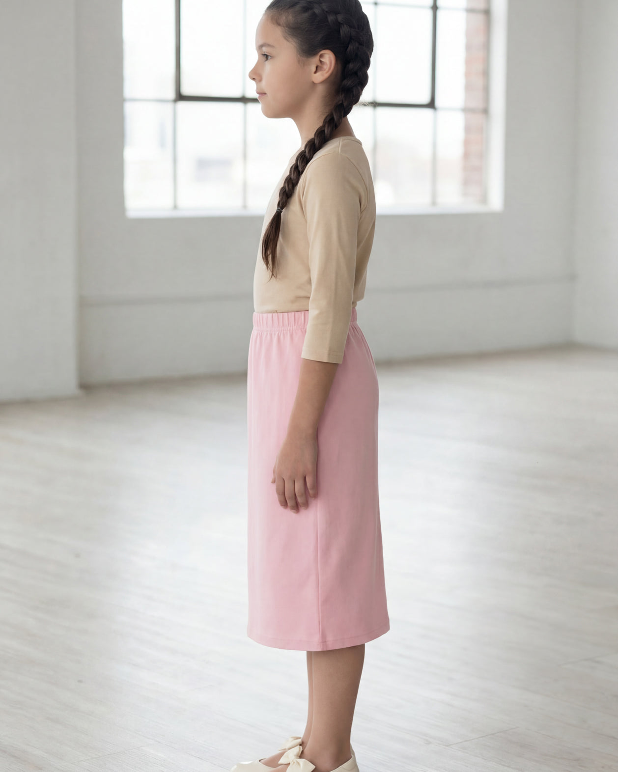 Model wearing the Nuggles® Girls' Classic Midi Skirt in Rose