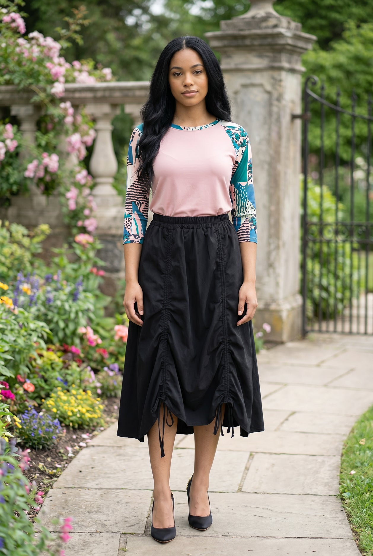 Woman in a garden wearing a floral top and black skirt