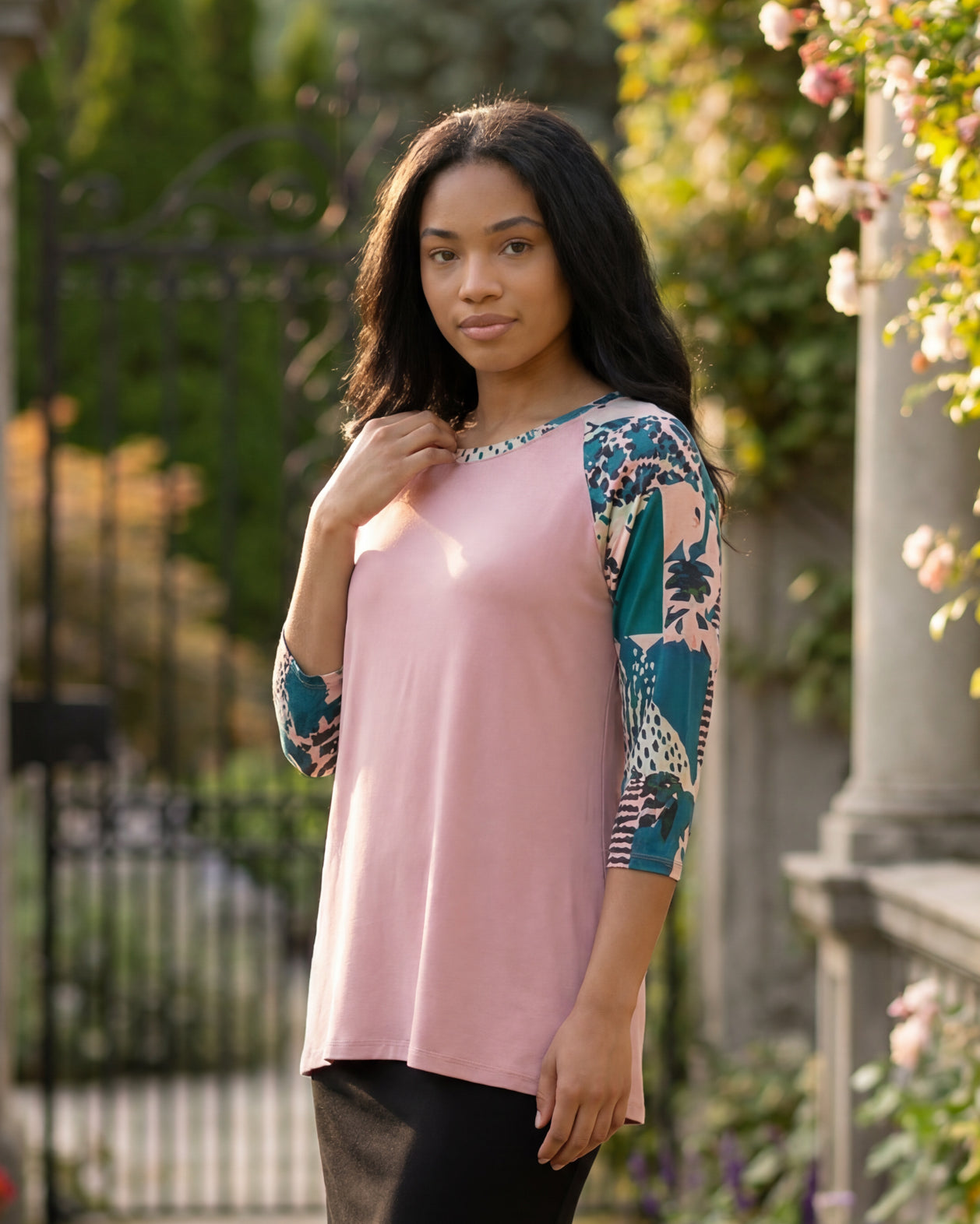Woman in a garden wearing a floral top and black skirt