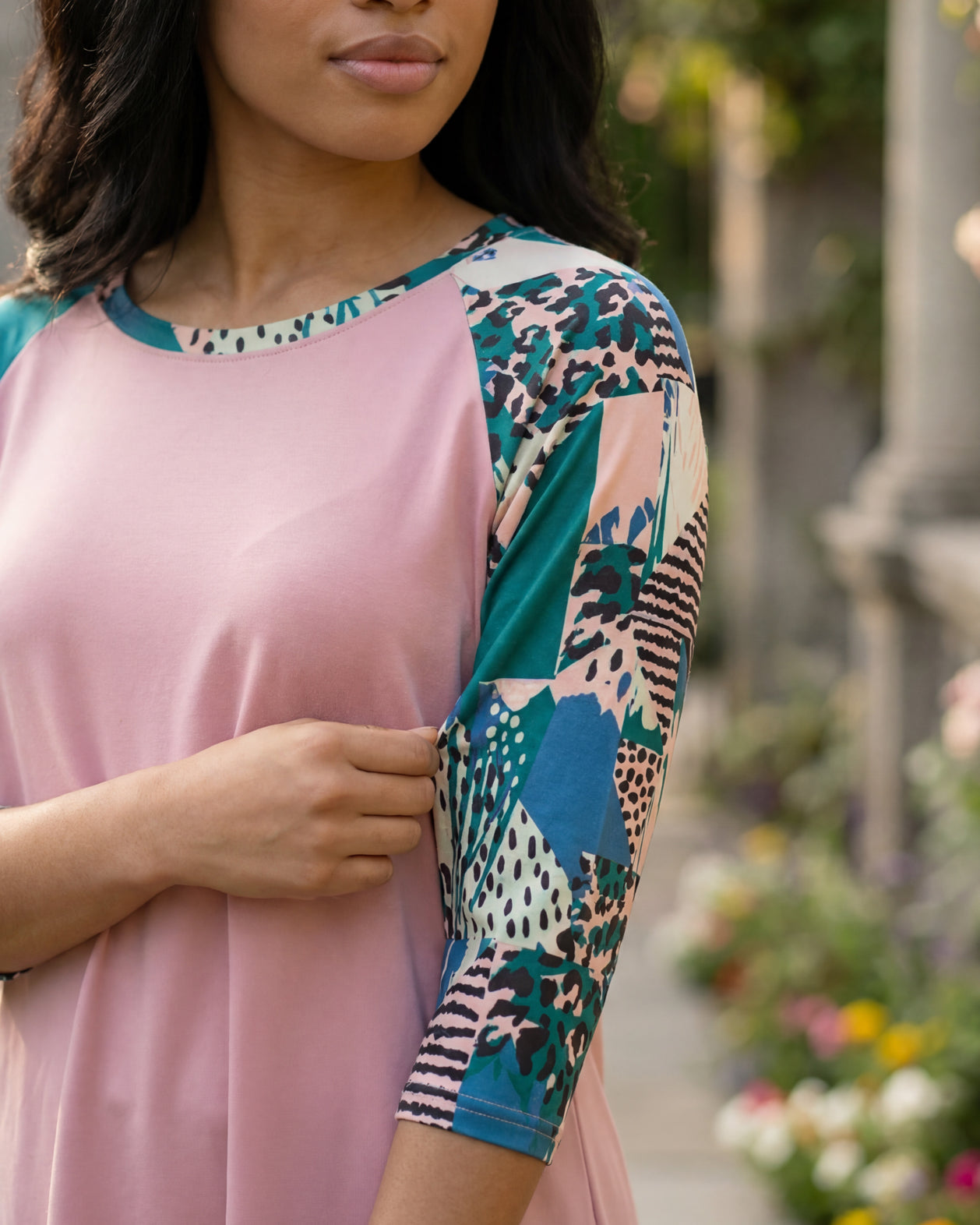 Woman in a garden wearing a floral top and black skirt